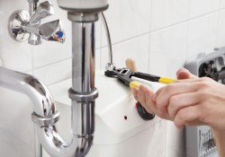 Young plumber fixing a sink in bathroom